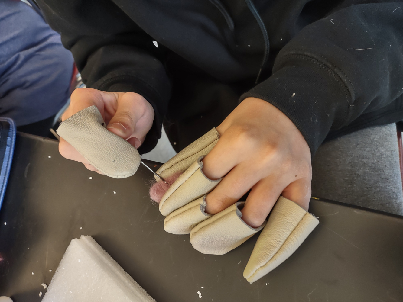 A student's hands protected by finger caps as they needlefelt.